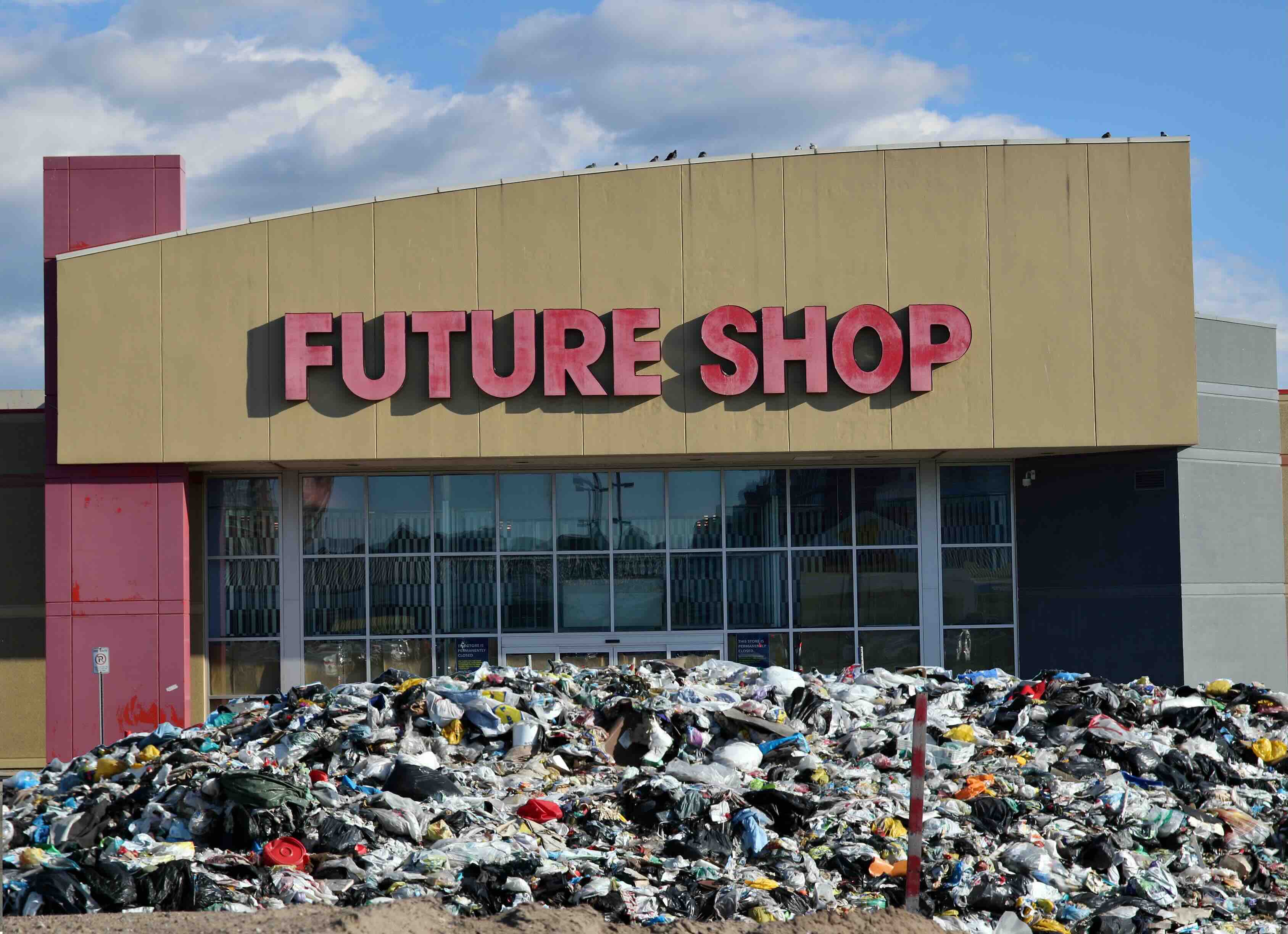 A photo of a large retail store called 'Future Store' with a landfill-like heap of garbage that is piled up to the doors of the store.