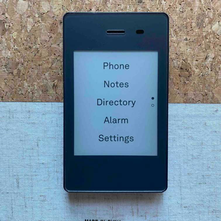 A photo of the Light Phone 2's home screen showing a list of tools, including Phone, Notes, Directory, Alarm, and Settings.